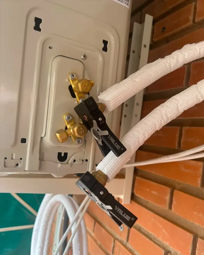Conexión de la línea frigorífica a la unidad exterior de un aire acondicionado en fachada de ladrillo